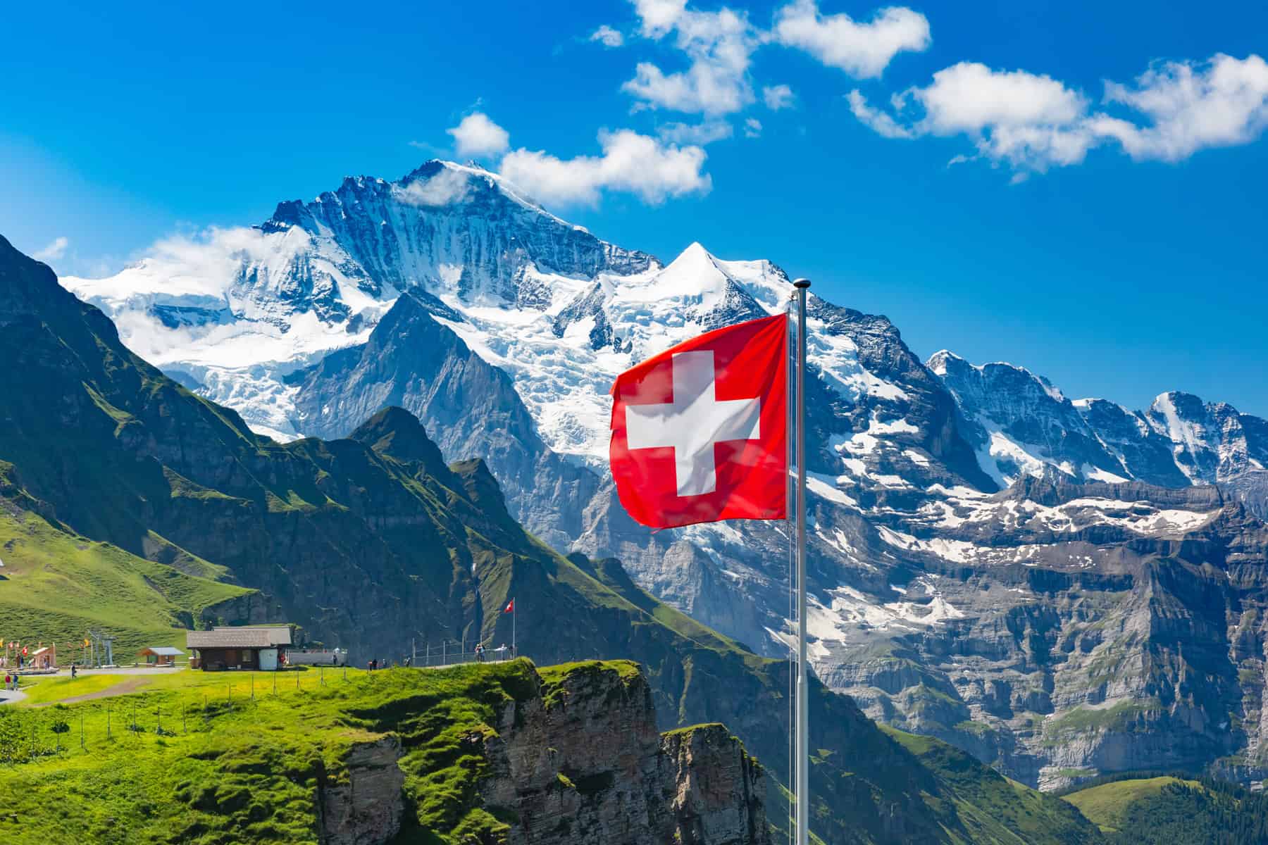 Wehende Schweizer Flagge vor imposanter Alpenkulisse – ein Zeichen für Herkunft, Qualität und Nachhaltigkeit aus der Schweiz.