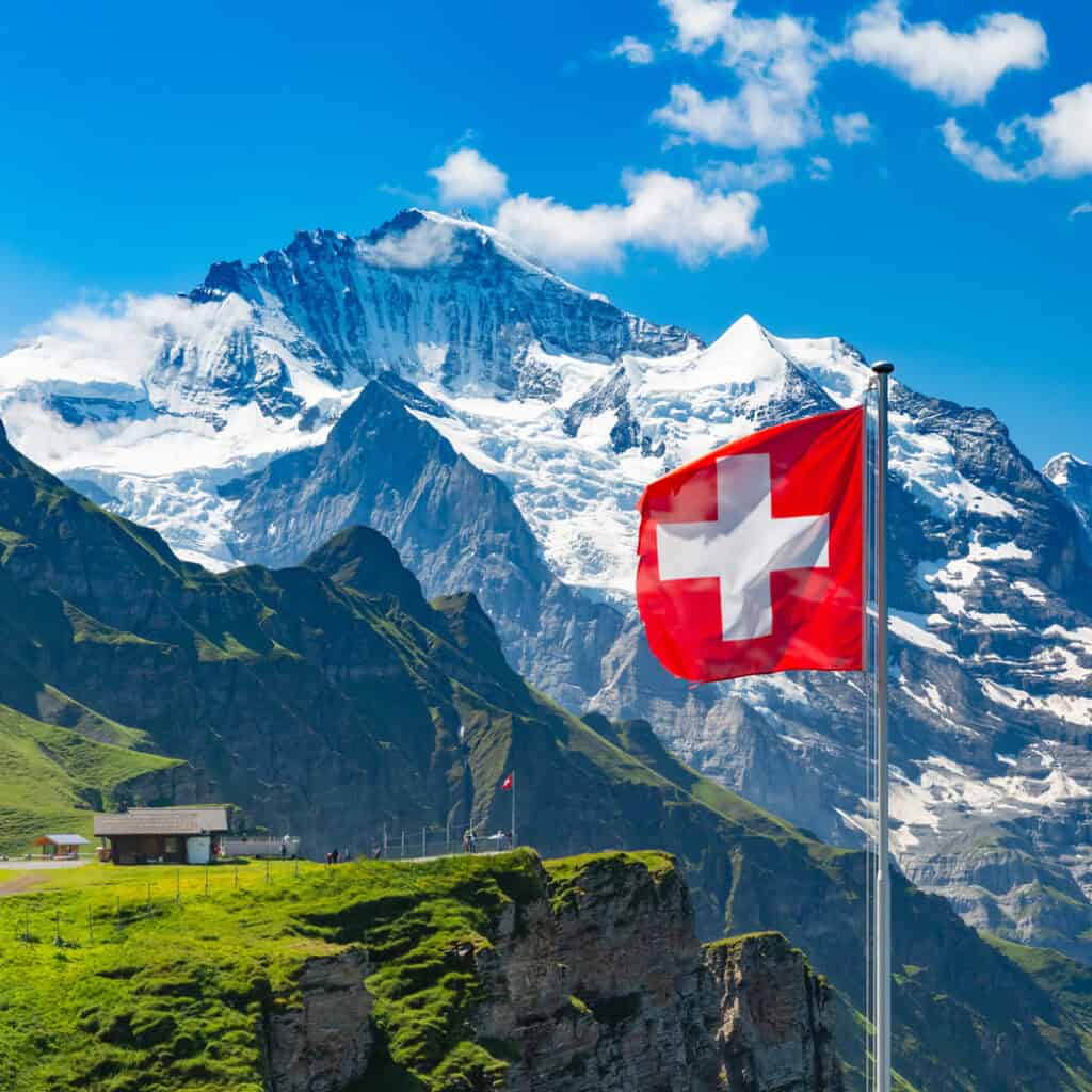Wehende Schweizer Flagge vor imposanter Alpenkulisse – ein Zeichen für Herkunft, Qualität und Nachhaltigkeit aus der Schweiz.