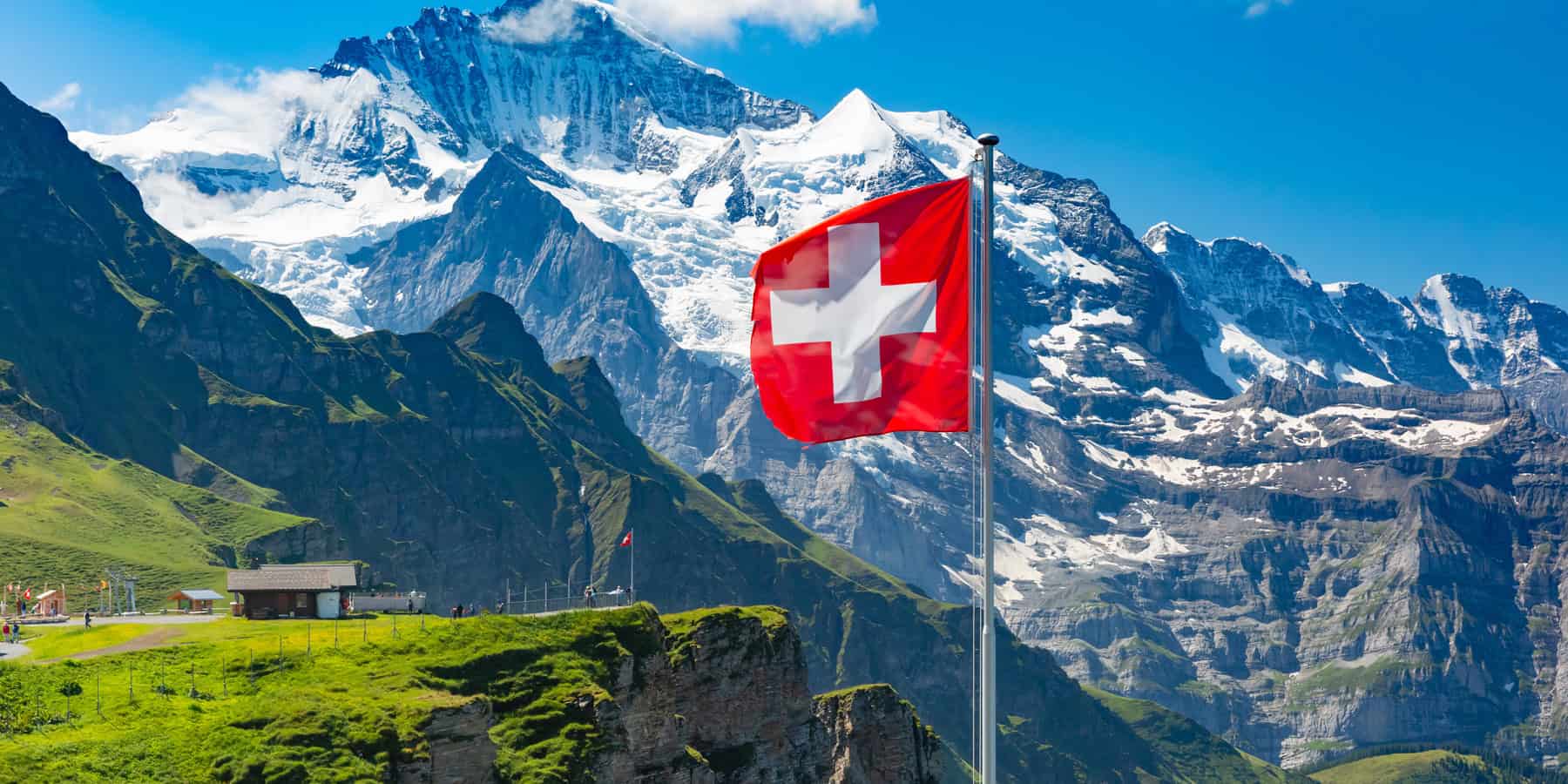 Wehende Schweizer Flagge vor imposanter Alpenkulisse – ein Zeichen für Herkunft, Qualität und Nachhaltigkeit aus der Schweiz.