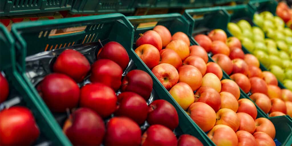 Frische Schweizer Äpfel in verschiedenen Farben in grünen Verkaufskisten.